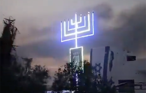 Thumbnail preview image for the video titled: In Shujaiia Neighborhood, a huge Hanukkah candle being raised over a civilian house
