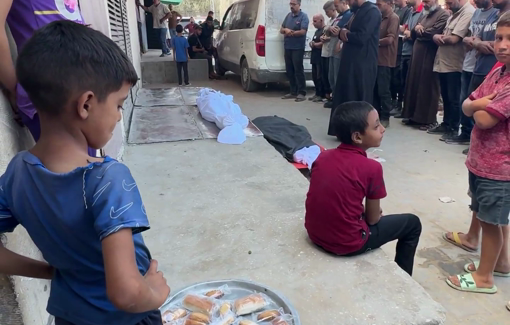 Thumbnail preview image for the video titled: Child sweets-seller stands in front of a funeral prayer at a hospital mortuary