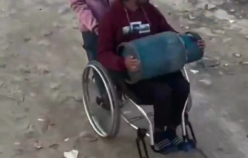 Thumbnail preview image for the video titled: A little girl struggles to pull her father’s wheelchair to transport a gas cylinder